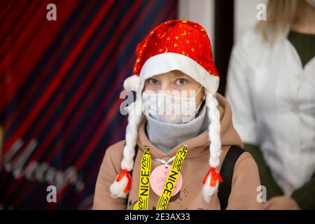 24 décembre 2020. Biélorussie, la ville de Gomil. Vacances de Noël dans la ville. Une fille portant un chapeau du père noël et un masque médical à la Hol de Noël Banque D'Images