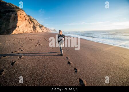 Une randonneur femelle descend une plage de Californie le soir, une partie de la piste des chutes d'Alamere dans le bord de mer national de point Reyes. Banque D'Images