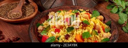 Panorama couscous avec des ingrédients sur fond de bois rustique sombre, dans le tajine traditionnel Banque D'Images