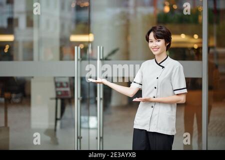 Une jeune femme heureuse et accueillante avec son concierge à l'intérieur de l'hôtel Banque D'Images