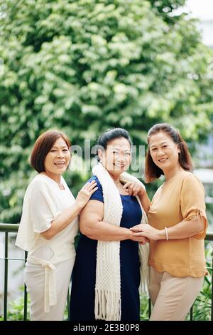 Groupe d'amis asiatiques matures vietnamiens heureux debout à l'extérieur et sourire à l'appareil photo Banque D'Images