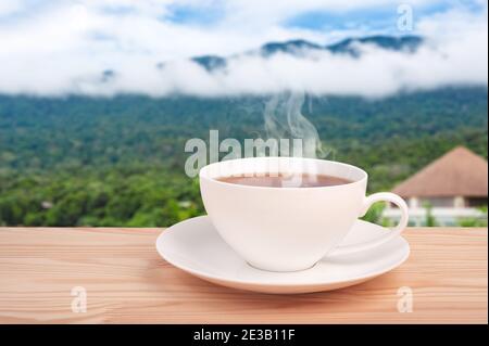Tasse de thé avec feuille de thé biologique sur la table en bois et les plantations de thé. Tasse de thé chaude. Espace pour le texte. Produit biologique de la nature pour une bonne santé wi Banque D'Images