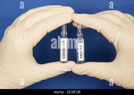 Les mains dans des gants médicaux tiennent les flacons du vaccin Covid. Gros plan Banque D'Images