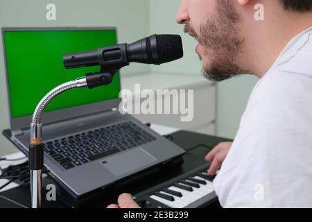 Homme méconnu blogueur, youtuber, influenceur enregistrant une vidéo jouant le piano électronique et chantant à la maison. Musicien, chanteur, pianiste. G Banque D'Images