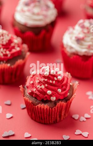 Bonbons de Saint-Valentin. Petits gâteaux décorés de perles sur fond rouge, gros plan Banque D'Images