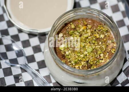 Vue de dessus d'un bol de Sutlac (Sütlaç) - dessert turc traditionnel aromatique, pudding crémeux de riz à la cannelle et aux pistaches, servi sur un an noir Banque D'Images