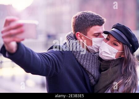 Couple heureux célébrant la Saint Valentin dans les masques pendant la pandémie de Covid-19 Banque D'Images