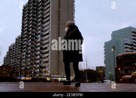 Leverkusen, Allemagne. 18 janvier 2021. Une femme passe devant un bâtiment résidentiel dans le quartier de Chorweiler et porte une protection de la bouche et du nez. Dans la pandémie de Corona en Rhénanie-du-Nord-Westphalie, un indicateur important a légèrement diminué, mais il reste à un niveau élevé. La chancelière Merkel et les chefs de gouvernement des États fédéraux veulent discuter mardi (19.01.2020) d'un éventuel resserrement des règles de verrouillage. Credit: Oliver Berg/dpa/Alay Live News Banque D'Images