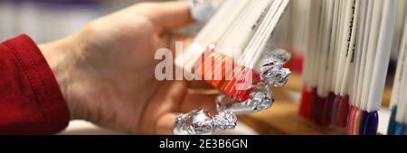 La main femelle avec du papier d'aluminium sur les ongles contient des échantillons de palette de couleur de clou. Banque D'Images