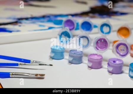 Peinture, art, concept de créativité. Pinceaux, un ensemble de peintures acryliques et un fragment de toile. Gros plan. Mise au point sélective. Banque D'Images