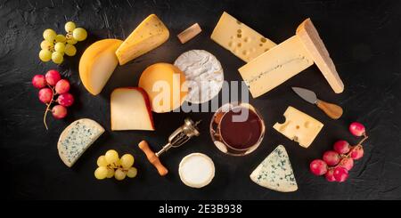 Panorama du fromage et du vin, fromages divers, tiré d'en haut sur fond noir avec des raisins Banque D'Images