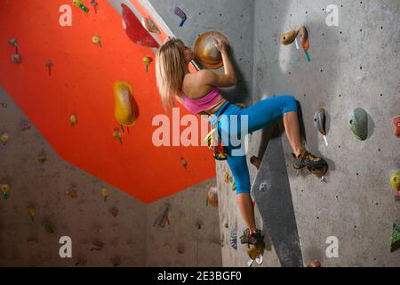 Jeune femme Climber Bouldering dans la salle d'escalade. Sport extrême et escalade en intérieur Banque D'Images