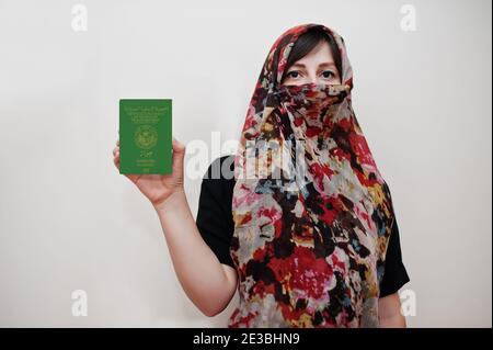La jeune femme musulmane arabe vêtue de hijab tient le passeport de la République islamique de Mauritanie sur fond de mur blanc, portrait de studio. Banque D'Images