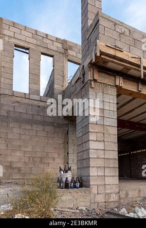 Bouteilles de bière empilées dans et autour d'un seau blanc de cinq gallons sur un chantier de construction. Banque D'Images