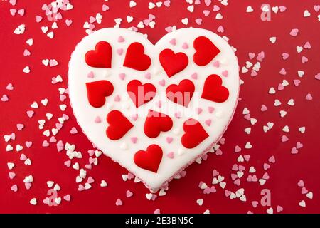 Gâteau de coeur pour la Saint-Valentin, la fête des mères ou l'anniversaire, décoré de coeurs de sucre sur fond rouge Banque D'Images