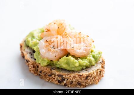 Toast à l'apéritif ou bruschetta avec crème d'avocat et crevettes isolées sur fond de marbre blanc Banque D'Images