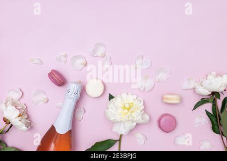 Composition printanière avec vin mousseux rose, pivoines blanches et macarons Banque D'Images