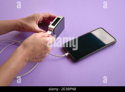 Une femme charge un téléphone portable avec une banque d'alimentation. Gros plan. Banque D'Images