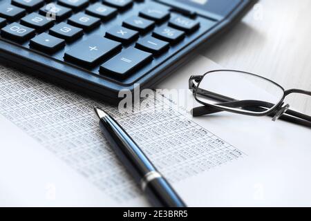 La vie d'affaires d'une calculatrice, de lunettes, d'un stylo à bille et d'une table avec des chiffres. Le concept de la déclaration, de la comptabilité. Banque D'Images