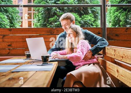 un jeune couple heureux dans un café derrière un ordinateur portable. le gars et la fille ont du plaisir souriant Banque D'Images