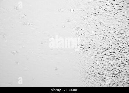 Image monochrome des éclaboussures d'eau de pluie sur la surface vitrée de la fenêtre du navire de croisière norvégien Banque D'Images