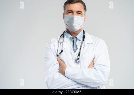 Joyeux médecin mature dans le masque facial posant à l'appareil photo, les soins de santé et la médecine. Banque D'Images