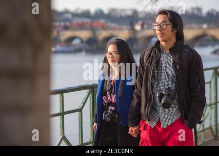 Prague, République tchèque. 09-23-2019. Le couple asiatique marche et profite le long de la Vltava avec le pont Charles en arrière-plan pendant un Banque D'Images