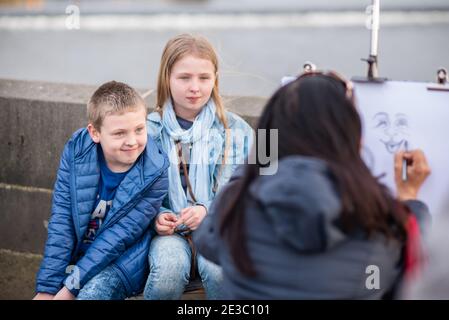 Prague, République tchèque. 09-23-2019. Des artistes de rue dessinant et peignant deux enfants touristes sur le pont Charles pendant une journée ensoleillée à Prague. Banque D'Images