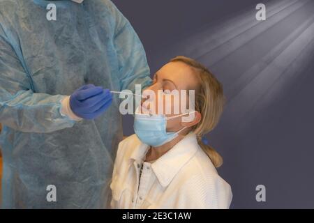 Un professionnel de la santé doté d'un équipement de protection effectue un écouvillonnage du coronavirus sur une jeune fille caucasienne. Écouvillon nasal pour Covid-19. Tests de laboratoire pour le coronavirus conc Banque D'Images