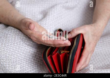 Une femme âgée prend une pièce de son portefeuille, froissée les mains de la femme en gros plan. Concept de pauvreté, paiements de pension, pensionné avec argent métallique Banque D'Images