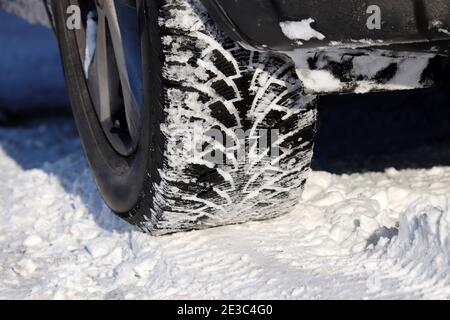 Roue de voiture recouverte de neige sur une route. Pneus d'hiver, conduite par temps froid et sur glace Banque D'Images