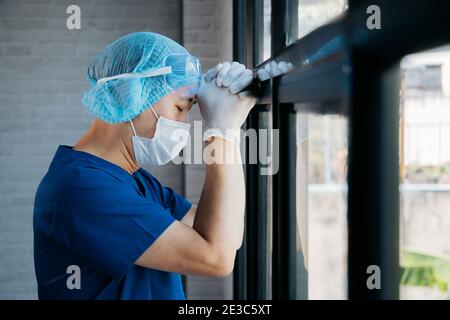 Travailleur médical masculin fatigué travaillant pendant des heures à l'hôpital. Asiatique surtravaillé professionnel se sentant somnolent et épuisé pendant l'épidémie de grippe pandémique COVID-19. Infirmière et médecin stressés et déprimés Banque D'Images