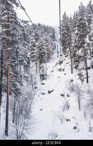 Télésiège sur la forêt enneigée d'hiver. Chaise remontée mécanique au-dessus des pins. Banque D'Images