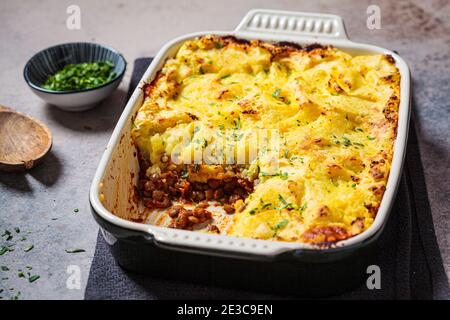 Tarte au berger végétalien avec lentilles et purée de pommes de terre dans un plat de fond noir. Concept alimentaire végétalien. Banque D'Images