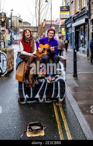 Un jeune couple Busking à Brick Lane, Londres, Royaume-Uni. Banque D'Images