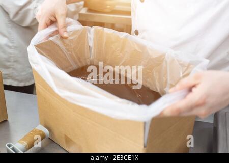 Emballage de chocolat chaud et de pâte de chocolat dans la fabrication de confiseries. Préparer du lait concentré de crème anglaise et de la crème pour les gâteaux Banque D'Images