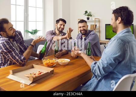 Groupe d'amis qui ont de la pizza et de la bière, regarder la télévision, parler et avoir du bon temps Banque D'Images