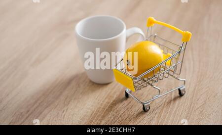 Citron dans un petit panier sur la table de cuisine. Une tasse de thé blanc se trouve à proximité. Cuisine moderne et lumineuse. Banque D'Images