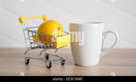 Citron dans un petit panier sur la table de cuisine. Une tasse de thé blanc se trouve à proximité. Cuisine moderne et lumineuse. Banque D'Images
