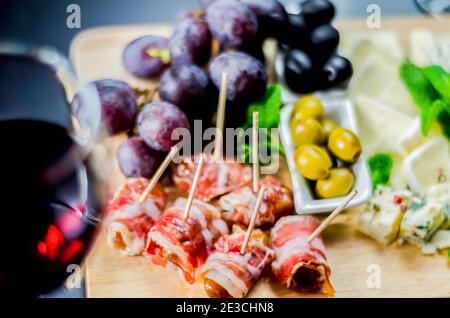 Délicieuses figues enveloppées de bacon, servies avec du fromage bleu, du raisin et des olives, service de restauration pour la fête Banque D'Images