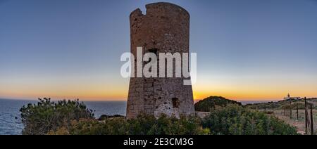 Image de la tour de guet du Cap blanc à Majorque avec le phare en arrière-plan au coucher du soleil.cette tour construite dans le s. XVI a mis en garde contre les attaques de pirates. Banque D'Images