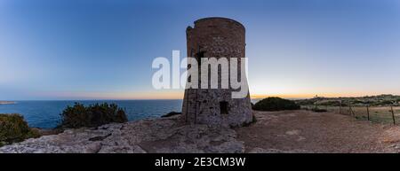 Image de la tour de guet du Cap blanc à Majorque avec le phare en arrière-plan au coucher du soleil.cette tour construite dans le s. XVI a mis en garde contre les attaques de pirates. Banque D'Images