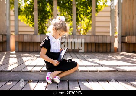 Retour à l'école et temps heureux mignon enfant industriel assis à l'extérieur. Fille lisant le livre Banque D'Images