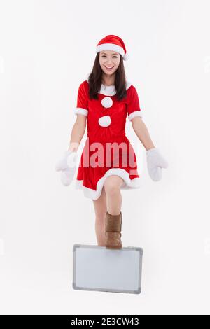 Portrait d'une jeune femme portant un chapeau de père noël, tenant le tableau blanc haut photo de qualité Banque D'Images