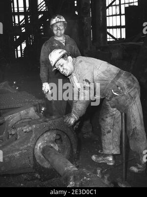 Deux ouvriers travaillant dans le brise-roche Huber de Blue Coal. Le Huber était un point de repère situé dans le quartier d'Ashley, canton de Hanovre, comté de Luzerne, Pennsylvanie, États-Unis. Le brise-roche a été construit en 1939 pour remplacer le brise-roche Maxwell qui était situé à la collierie. Le charbon de mine arrivant au brise-roche a été lavé et nettoyé pour éliminer les impuretés, principalement l'ardoise. Il a été écrasé et filtré aux tailles spécifiques souhaitées par les clients. Considéré comme une usine ultra-moderne lorsqu'il est construit. Il a traité 7,000 tonnes de charbon d'Anthracite par jour. Le produit final a été pulvérisé avec un colorant bleu et vendu sous le nom de «Blu Banque D'Images