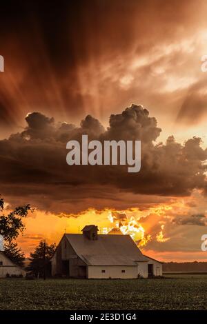 Un orage semble se former au-dessus d'une ancienne grange près de Brownstown, DANS. Certains rayons crépusculaires sortent du sommet du nuage. Banque D'Images