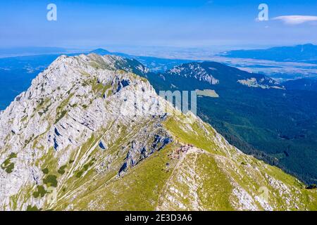 Randonneurs sur un sommet rocheux des Carpates roumains, scène estivale dans le massif de Piatra Craiului et vue depuis le sommet. Banque D'Images