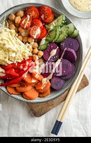 bol budha avec batata pourpre, poivrons, chou, patates douces, pois chiches, concombres sur la nappe blanche en lin Banque D'Images