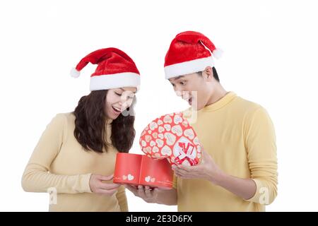 Portrait d'un jeune couple portant des chapeaux de père Noël tenant des cadeaux haut photo de qualité Banque D'Images