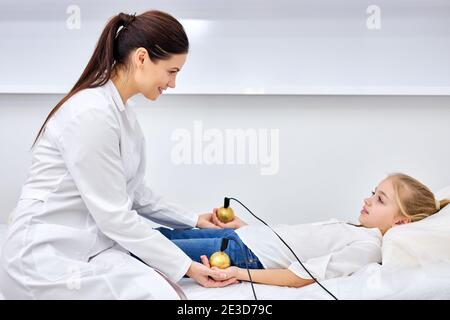 femme médecin thérapeute traitant l'enfant patient à l'aide d'un stimulateur électrique pendant Ou en cours d'acupuncture.TENS Transcutané électrique ne Banque D'Images